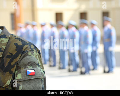 Soldato dell'esercito uniforme con bandiera della Repubblica ceca a Praga durante il cambio della guardia nel castello e una pattuglia di guardie Foto Stock