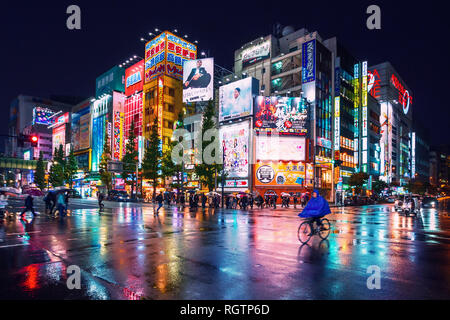 Luci al neon e cartelloni pubblicitari su edifici di Akihabara a notte piovosa, Tokyo, Giappone Foto Stock