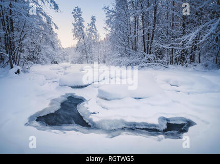 Scenic inverno paesaggio con fiume che scorre e la luce del mattino in Finlandia Foto Stock