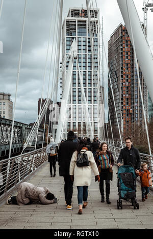 London, Regno Unito - 26 Gennaio 2019: persona senzatetto in una posizione di preghiera implorando su Hungerford Bridge vicino alla stazione di Waterloo, Londra Foto Stock