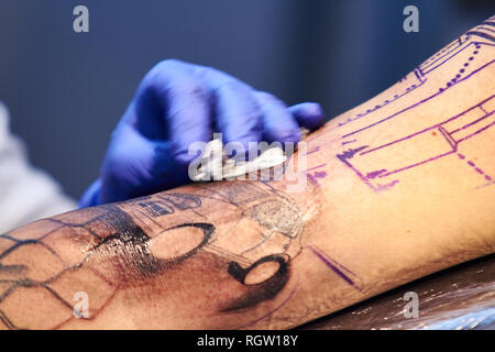 Tattoo Artist pulizia di un tatuaggio onworking con guanti blu Foto Stock