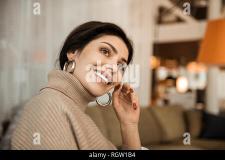 Trasmissione via IR di attraente dama con i capelli scuri premurosamente seduta sul lettino Foto Stock