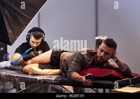 ALICANTE TATTOO FAIR CIRCA 2018 concentrata tatuaggio artista che lavora su un design di gamba Foto Stock