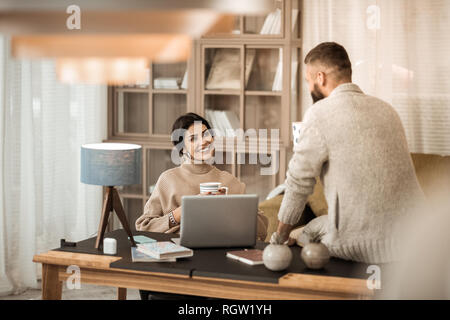 Attraente coppia positiva avente conversazione insieme mentre è seduto in angolo ufficio Foto Stock