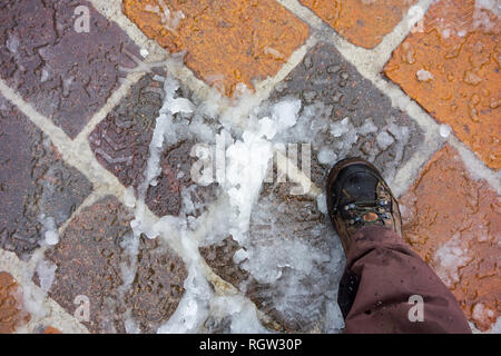 Scarpa sulla neve bagnata / nevischio sulla pavimentazione sdrucciolevole / marciapiede in inverno Foto Stock