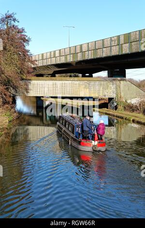 Una barca stretta sulla giunzione del Wey di navigazione e Basingstoke canal a New Haw, con la sezione in alzata del M25 Autostrada,Surrey in Inghilterra Foto Stock