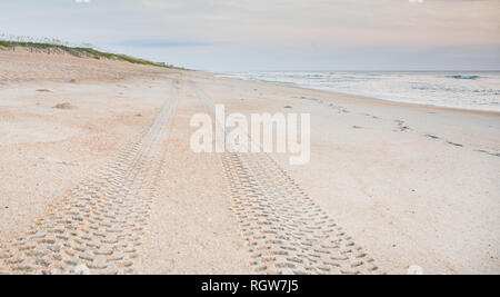 Impronte del battistrada nella sabbia che conducono fuori nella distanza sulla spiaggia. Foto Stock