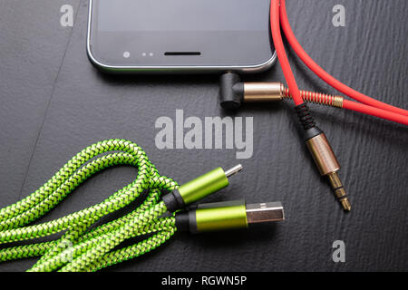 Jack e cavo usb per smartphone. Il telefono e gli accessori sul tavolo.  Sfondo scuro Foto stock - Alamy