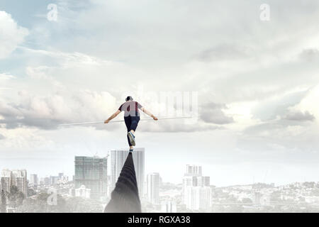 Ropewalker in black hat corda a piedi in alto nel cielo . I supporti misti Foto Stock