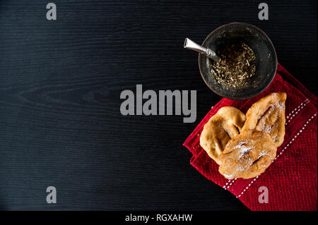 Cultura latinoamericana: Mate infusione e torta frita su uno sfondo scuro. Foto Stock