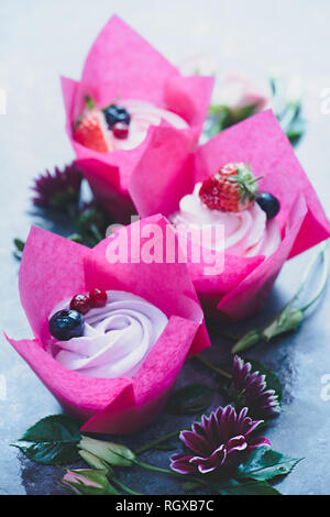 Tortine con rosa avvolge e rose fiori su uno sfondo scuro. La molla dessert per tre con spazio di copia Foto Stock