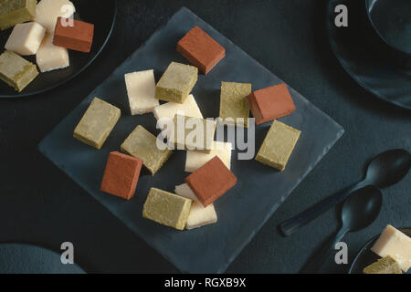 Assortimento di cioccolatini morbido su uno sfondo nero con copia spazio. Latte e matcha giapponese cioccolato gourmet close-up Foto Stock