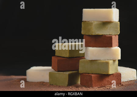 Assortimento di cioccolatini morbido su uno sfondo nero con copia spazio. Latte e matcha giapponese cioccolato gourmet close-up Foto Stock