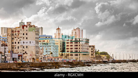 Il Malecon street embankment e oceano Atlantico onde, con colorati Havana city in background con nuvole grigie, Cuba Foto Stock