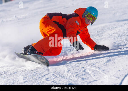 Un maschio snowboarder intaglia un giro sulle piste francesi nella località alpina di Courchevel. Foto Stock