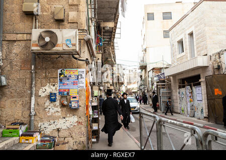 Gerusalemme, Israele - Dicembre 24th, 2018: una scena di strada con due man in black, donazioni di beneficenza nelle caselle sulla parete in ultra ortodosso distretto. Foto Stock