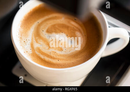 Tazza di cappuccino closeup con crema soffice schiuma di latte, vista dall'alto sulla macchina per caffè , caffè appena fatto Foto Stock