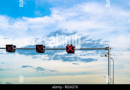 Segnale di traffico in luce con il colore rosso del segno a forma di croce sul cielo blu e nuvole bianche sfondo. Segno errato. Nessuna voce segno di traffico. La croce rossa di arresto di orientamento Foto Stock