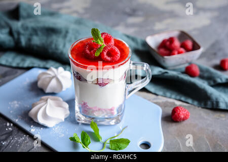 Deliziosi dessert a strati con meringa frantumata baci, ricotta, di lamponi e panna montata in un vasetto di vetro Foto Stock