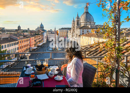 Una donna gode di vista di Roma, Italia e Piazza Navona come lei finisce la sua prima colazione da un tetto a terrazza di un hotel di lusso a inizio estate mattina Foto Stock