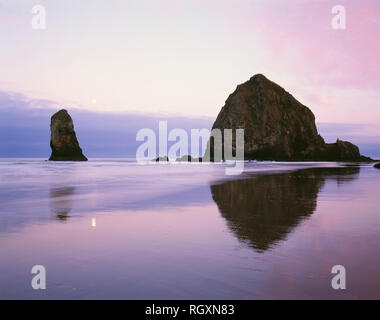 Stati Uniti d'America, Oregon, Cannon Beach, Dawn sky e calare della luna su Haystack Rock e gli aghi. Foto Stock