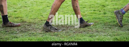 Close up foto di ragazzi gambe e sneakers coperto di fango dopo un cross country si incontrano. Foto Stock