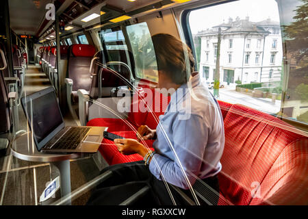 Business donna lavora sul computer portatile in prima classe in un treno in Svizzera. Foto Stock