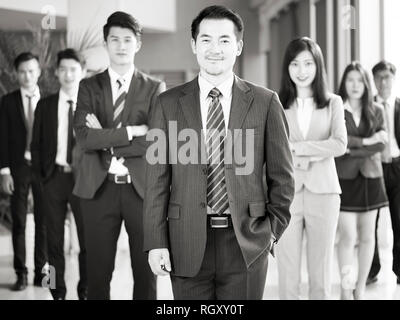 Ritratto di un team di successo di imprenditori asiatici e imprenditrici, guardando la telecamera sorridendo, in bianco e nero. Foto Stock