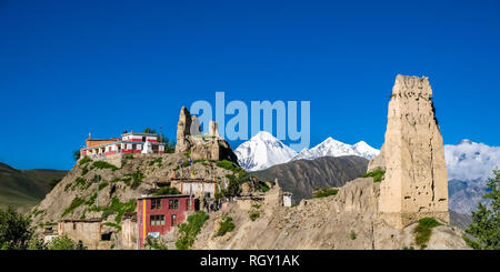 Vista sul monastero del villaggio con le rovine della fortezza, la coperta di neve il vertice di Mt. Dhaulagiri nella distanza Foto Stock