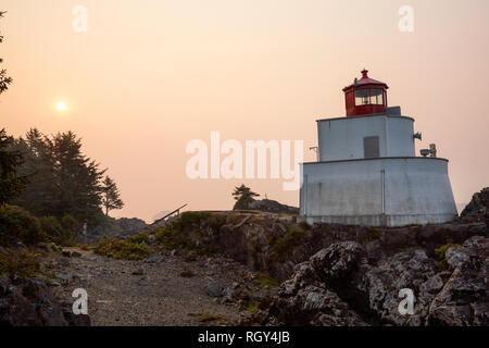 Faro sulla costa dell'Oceano Pacifico durante una vibrante sunrise. Amphitrite Point Lighthouse, Ucluelet, Isola di Vancouver, BC, Canada. Foto Stock