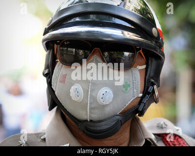 Royal Thai motociclo funzionario di polizia indossa occhiali da sole con mirroring e una maschera facciale protettiva nell'inquinamento di Bangkok. Foto Stock