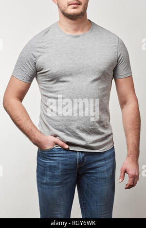 Vista ritagliata dell uomo con la mano in tasca in t-shirt con copia spazio isolato su grigio Foto Stock