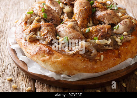 Musakhan pollo con sommaco, i pinoli e le cipolle su un pane piatto closeup sul tavolo. Posizione orizzontale Foto Stock