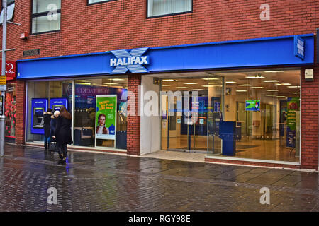 Persone che passano di fronte all'Halifax Bank locali, in Caroline Street, Bridgend Town Center, nel Galles del Sud. Atm / bancomat in parete. Foto Stock