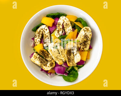 Halloumi insalata in una ciotola bianca isolata su uno sfondo giallo Foto Stock