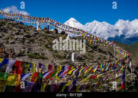 Piccolo chorten, gli stupa, sono situati sopra la città e colorati di preghiera buddista bandiere svolazzanti in aria, la coperta di neve il vertice di Mt. Dhaulagiri nel Foto Stock