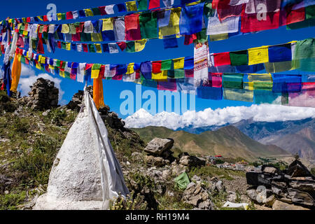 Piccolo chorten, gli stupa, sono situati sopra la città e colorati di preghiera buddista bandiere svolazzanti in aria, la coperta di neve il vertice di Mt. Dhaulagiri nel Foto Stock