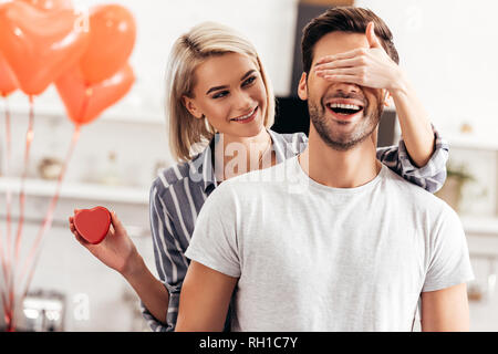 Messa a fuoco selettiva di attraente ragazza abbracciando e dando regalo al bel ragazzo il giorno di San Valentino Foto Stock