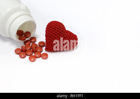 Pillole e maglia rossa cuore isolato su bianco. Concetto di ipertensione, antidepressivi, la pressione sanguigna e il cuore per il trattamento della malattia Foto Stock