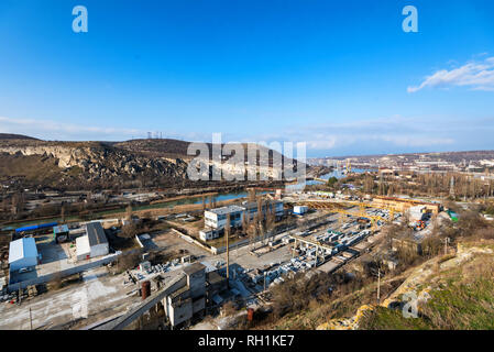 Zona industriale di una città vicino a un fiume con attrezzature per l'edilizia Foto Stock