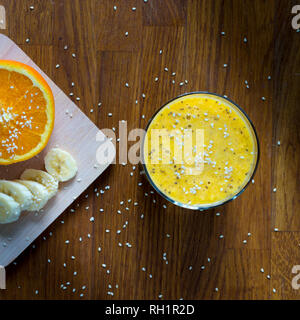 Banana sani e orange smoothie è un alimento molto sano per la prima colazione il colpo da overhead su un marrone tavolo in legno Foto Stock