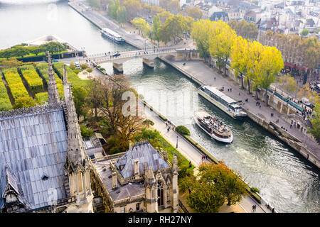 Vista aerea dalla torre della cattedrale di Notre Dame de Paris cathedral sul Fiume Senna con tour barche di crociera e persone che passeggiano sui pontili. Foto Stock