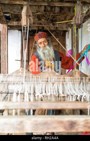 Kullu, Himachal Pradesh, India - 09 Agosto 2018 : Un indiano vecchio uomo fa un tradizionale sadu tessitura. Facendo una Pattu Sarees in Himalaya Foto Stock