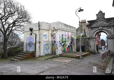 Coperto di graffiti e soggetto ad atti vandalici vecchio in disuso servizi igienici pubblici presso l'entrata di Queens Park in Brighton East Sussex Regno Unito Foto Stock