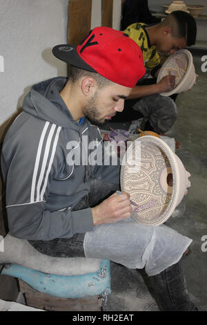 Giovani uomini pittura ciotole di ceramica in un ceramiche co-operativa in Fez, in Marocco Foto Stock