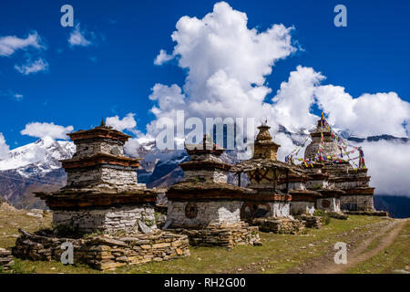 Un gruppo di chorten, gli stupa, è situato all'entrata del villaggio, coperta di neve la gamma della montagna di distanza Foto Stock