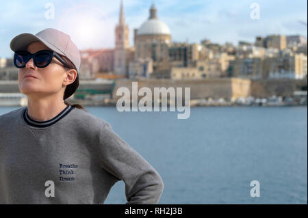 In prossimità di una rilassata donna che indossa una felpa con lo slogan "respirare, pensare, sogno". La Valletta, Malta sfondo. Foto Stock