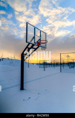 Coperta di neve outdoor basketball al tramonto Foto Stock