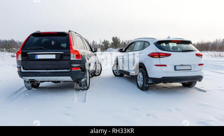 Il bianco e il nero di un suv auto parcheggiate in un campo nevoso. Vista posteriore. Foto Stock
