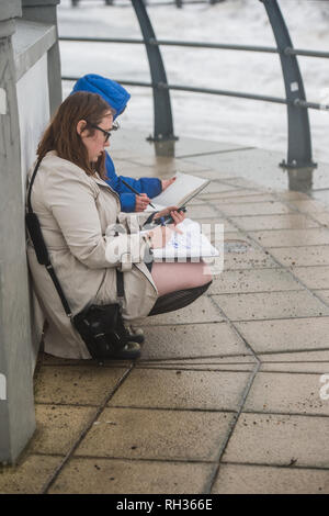 Due giovani studenti donne a Aberystwyth University School of Art oudoors disegno e delineando le onde causati dalla tempesta Diana Wales UK Foto Stock